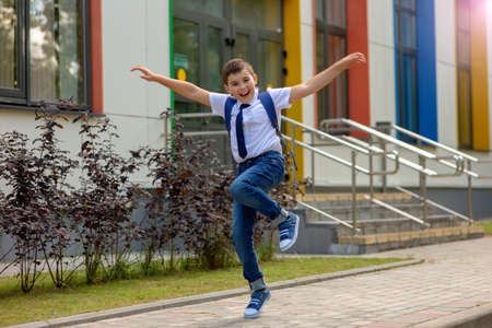 Cheerful fun young schoolboy jumping against school.の写真素材