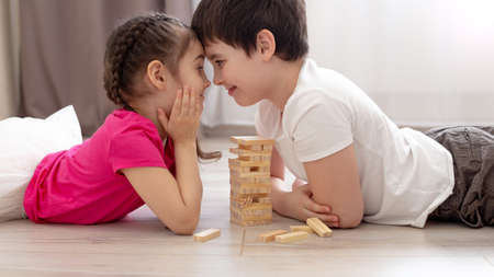 Smiling fun two children playing wooden game on the floorの写真素材