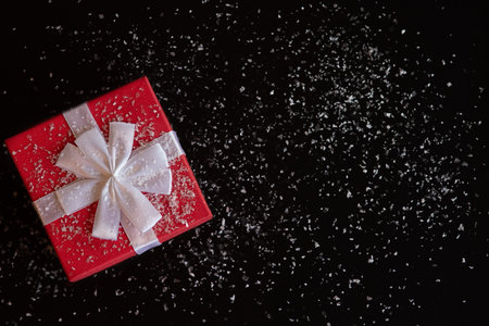Red gift box with a white bow on a black background