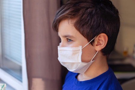 Brunette boy in blue clothes and white medical mask