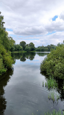 View of a beautiful lake in the forest among green trees with beautiful reflection, in...