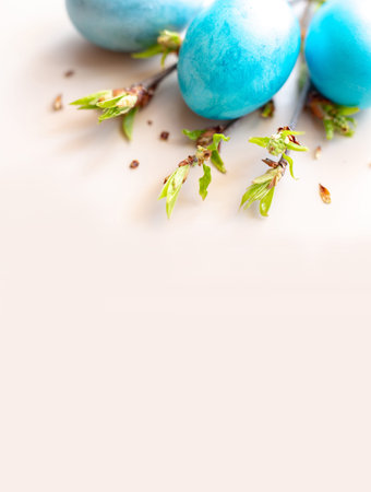 Three blue Easter eggs, and spring twigs with green leaves on a white table