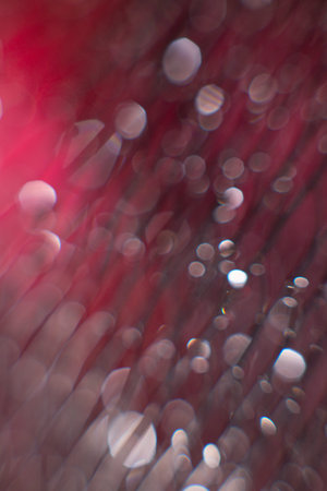 glare from water on a black mesh on a blurred red background. Abstract background