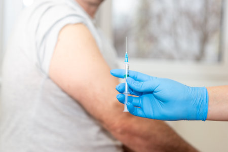 Close up - hand in blue gloves holding a small medical syringeの写真素材