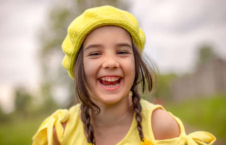 Outdoor shot portrait of a little adorable happy girl in a yellow knitted beretの写真素材