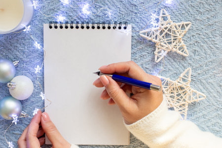 Womens hands over a white sheet of notebook, hold a blue fountain pen