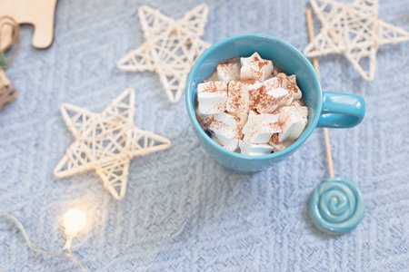 Blue mug with cocoa marshmallows, blue lollipop against the background of Christmas decorの写真素材