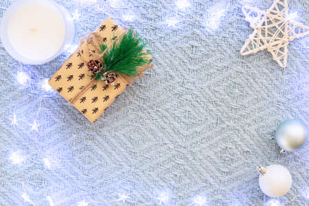 Blue knitted blanket with a glowing garland, a small gift with a sprig of spruceの写真素材