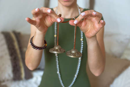 womans hand in holding oriental bells for yoga and meditation.の写真素材