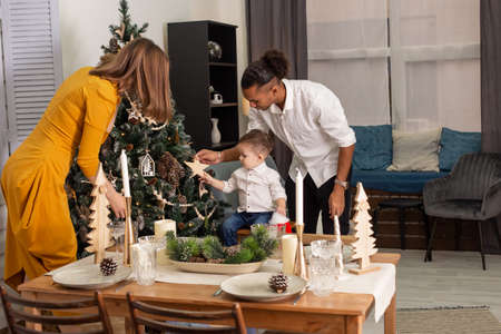 A young family is decorating a Christmas tree in the living room.の写真素材