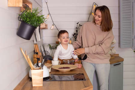 Young woman and little son play in the kitchen with dry red beans, togetherの写真素材