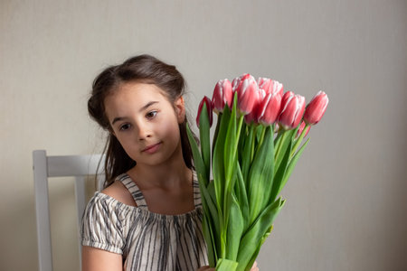 Portrait of a beautiful romantic little girl with a bouquet of pink tulipsの写真素材