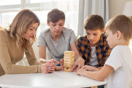 A family, three boys and a woman, are enthusiastically playing a board gameの写真素材