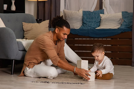 father and little son playing cubes on the floor of the room