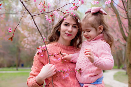 Portrait of mother and daughter in the park with blooming pink sakuraの写真素材