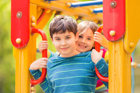 Smiling cute boy and girl, brunettes, stand among the yellow colorful playgroundの写真素材