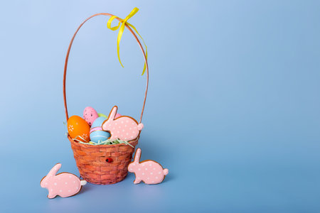 Cute pink gingerbread in the form of a rabbit and a basket with decorative Easter eggsの写真素材