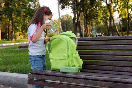 Young girl with backpack and water bottle in park settingの写真素材