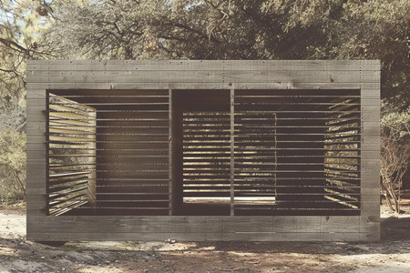 Modern wooden structure in a serene forest setting.の素材