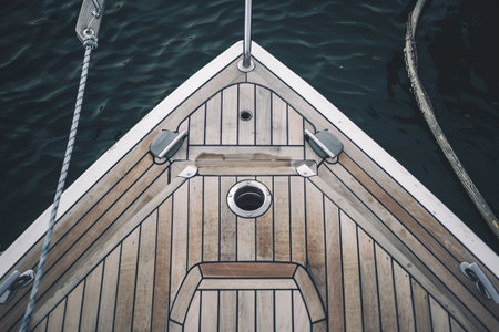 Wooden yacht deck with stainless steel fittings over calm waterの素材