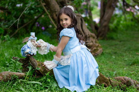 Young caucasian girl in blue dress playing in forest with toy rabbitの写真素材