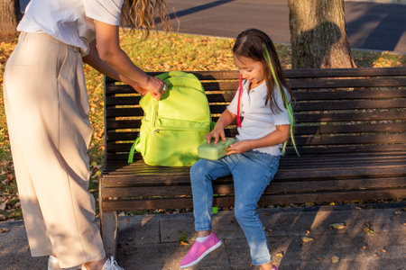 Child with green backpack on park bench at sunsetの写真素材