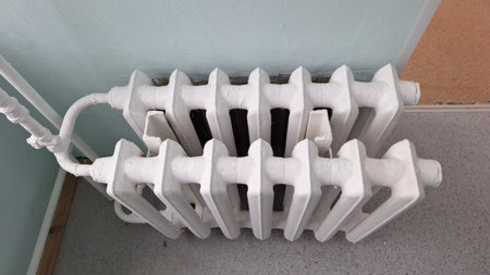 Antique white cast iron radiator in corner on gray floorの写真素材