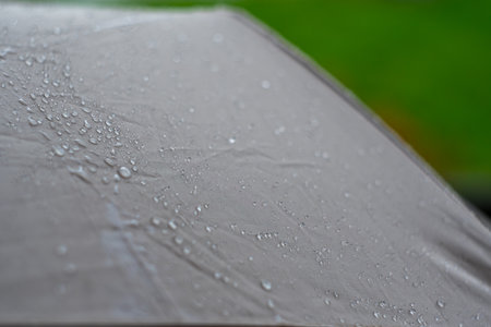 Close-up of rain-drenched umbrella surface with water dropletsの写真素材