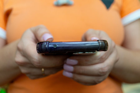 Young hispanic female using smartphone in casual orange shirtの写真素材