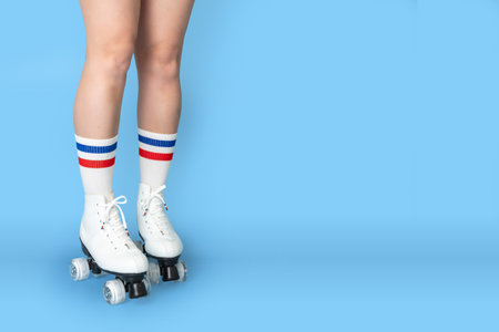 Close-up of legs with white roller skates and striped socks on blue backgroundの写真素材