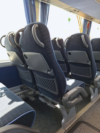 Empty bus interior with modern blue reclining seats and tray tablesの写真素材