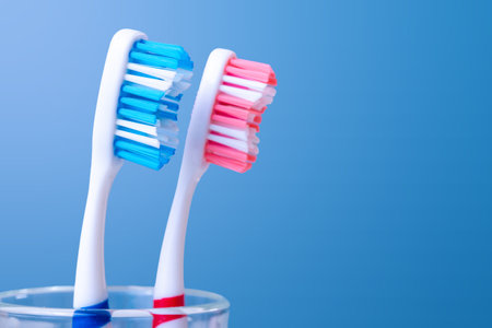 Close-up of blue and red toothbrushes in glass on blue backgroundの写真素材