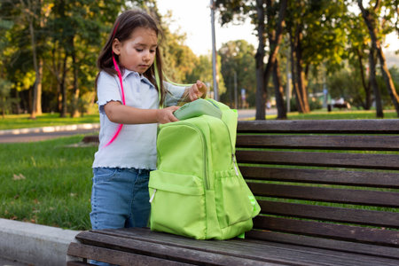 Young girl with backpack on park bench: exploring nature and outdoor learningの写真素材