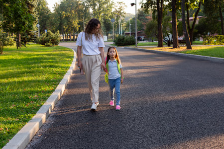 Mother and daughter walking on park pathway in casual outfitsの写真素材