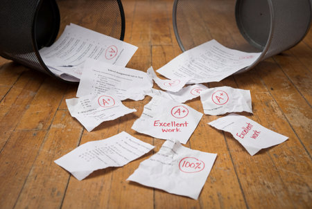 Torn A grade papers and trash bins on wooden floorの素材