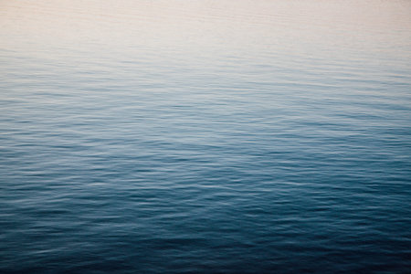 Close-up of water texture, smooth blue waves of water on the shore beach, color landscape photo of...