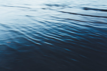 Close-up of water texture, smooth blue waves of water on the shore beach, color landscape photo of...