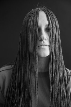 studio black and white portrait of a girl with African zizi braids, emotions on the face of a young...