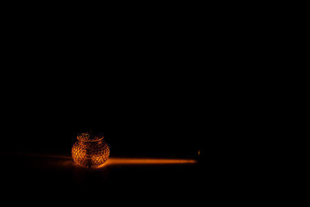 color photo of a glass vessel for a tea ceremony, close-up of the glass texture illuminated with a bright orange light on a dark backgroundの写真素材