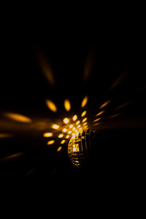 Color photo of a disco ball with orange lighting, a close-up play of light and shadow. Christmas and holiday conceptの写真素材