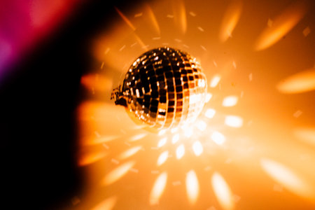 Color photo of a disco ball with orange lighting, a close-up play of light and shadow. Christmas and holiday conceptの写真素材