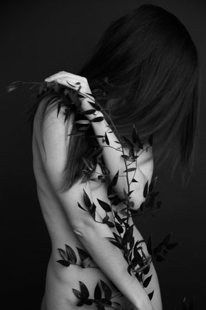 Black and white studio photo, naked girl and branch of beautiful exotic plant on body. Art photography, art and fashionの写真素材