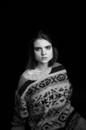 emotions of sadness and frustration on the face of a young girl, black and white authentic portrait of facial expressions on a dark background in the studioの写真素材