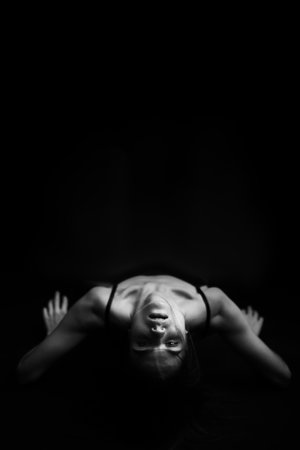 black and white creative photo shoot, the brunette poses unusually for the camera lying on the floor. art photography and non-trivial posingの写真素材