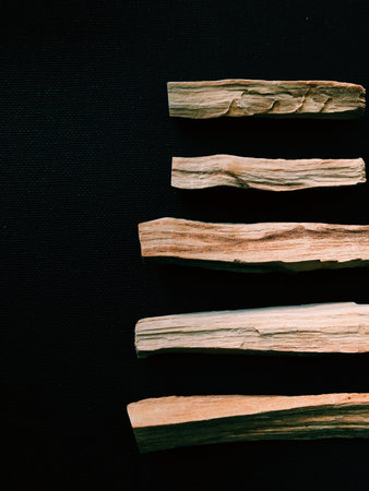 Scattered sticks of Palo Santo tree on a dark background. Top view. Organic holy tree incense from...