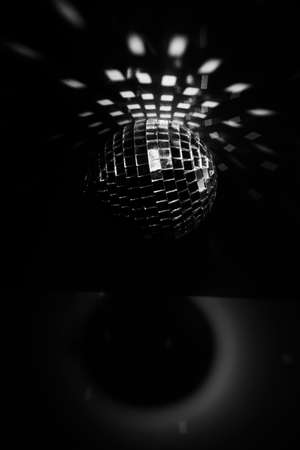 Black and white photo of a disco ball with orange lighting, a close-up play of light and shadow. Christmas and holiday conceptの写真素材