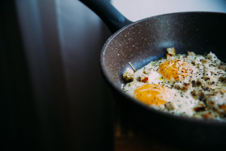 fried eggs in a frying pan, with cheese and chicken, stylish serving of dishes in a cafe and restaurantの写真素材