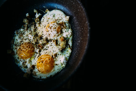 fried eggs in a frying pan, with cheese and chicken, stylish serving of dishes in a cafe and restaurantの写真素材