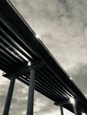 black and white film photo of a bridge over a river, dark urban landscape