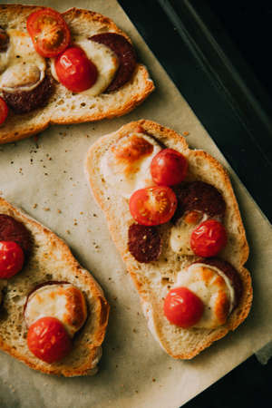 hot ciabatta sandwiches with pepperoni sausage, cheese and cherry tomatoes on parchmentの写真素材